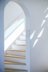 Escalier tournant blanc derrière un cadre de porte
